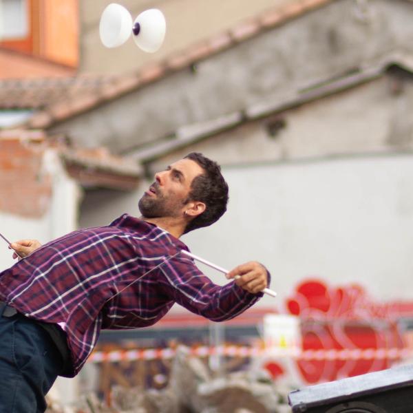 Sur un chantier d'un bâtiment démoli, l'artiste fait sauter son diabolo. Il se courbe vers l'arrière, le diabolo au-dessus de lui. Deux grosses enceintes sont posées sur les tas de gravas.