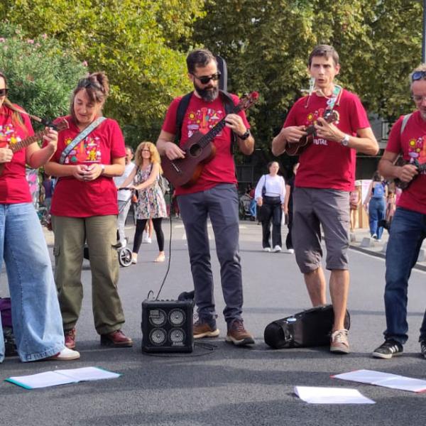 Neuf musiciens et musiciennes du groupe avec leurs instruments, dans une rue de Ramonville lors du Festival de rue