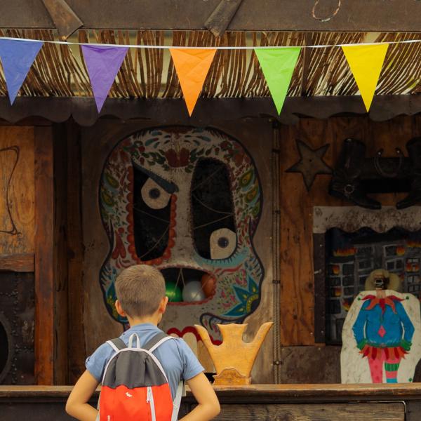 Une femme et un enfant, de dos, regardent le stand de tir, décoré de fanions.