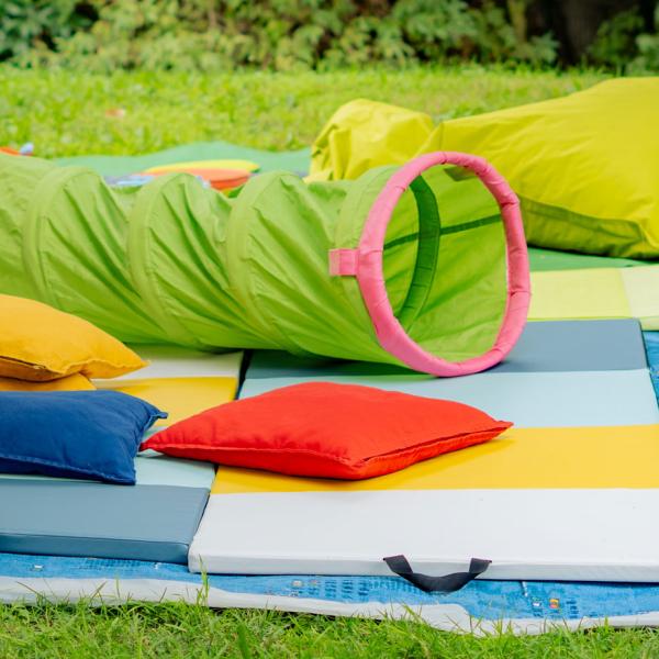 Espace pour les enfants avec tapis, coussins et jeux colorés.