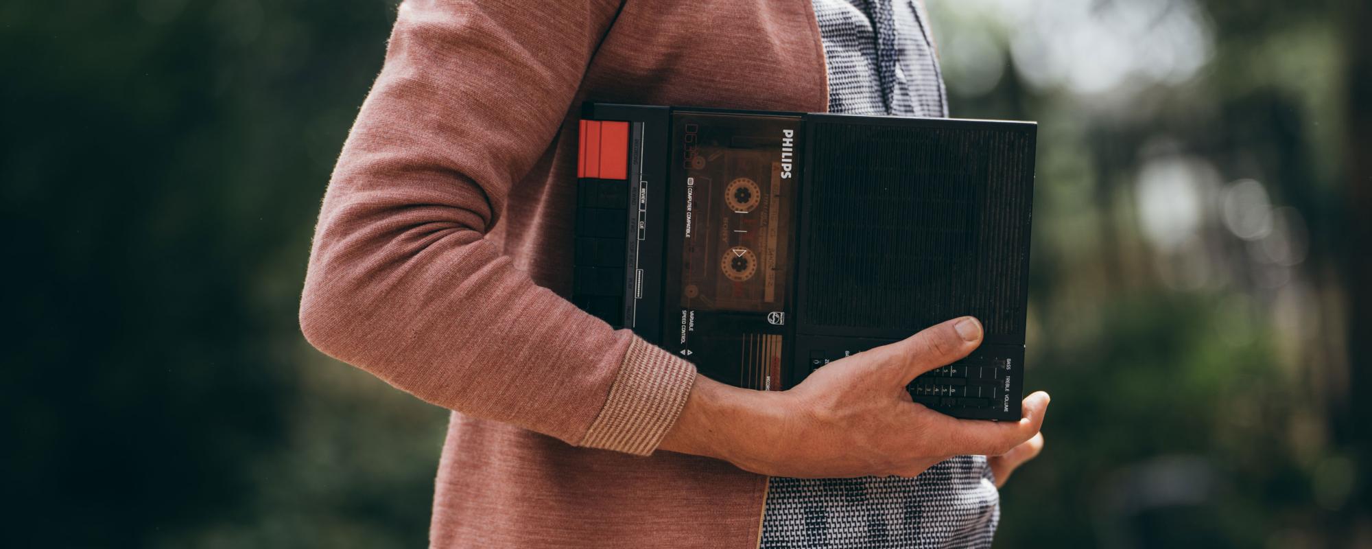 © Loïc Nys Quelqu'un dont on ne voit que le buste tient sur son bras un lecteur de cassettes portable Philips.