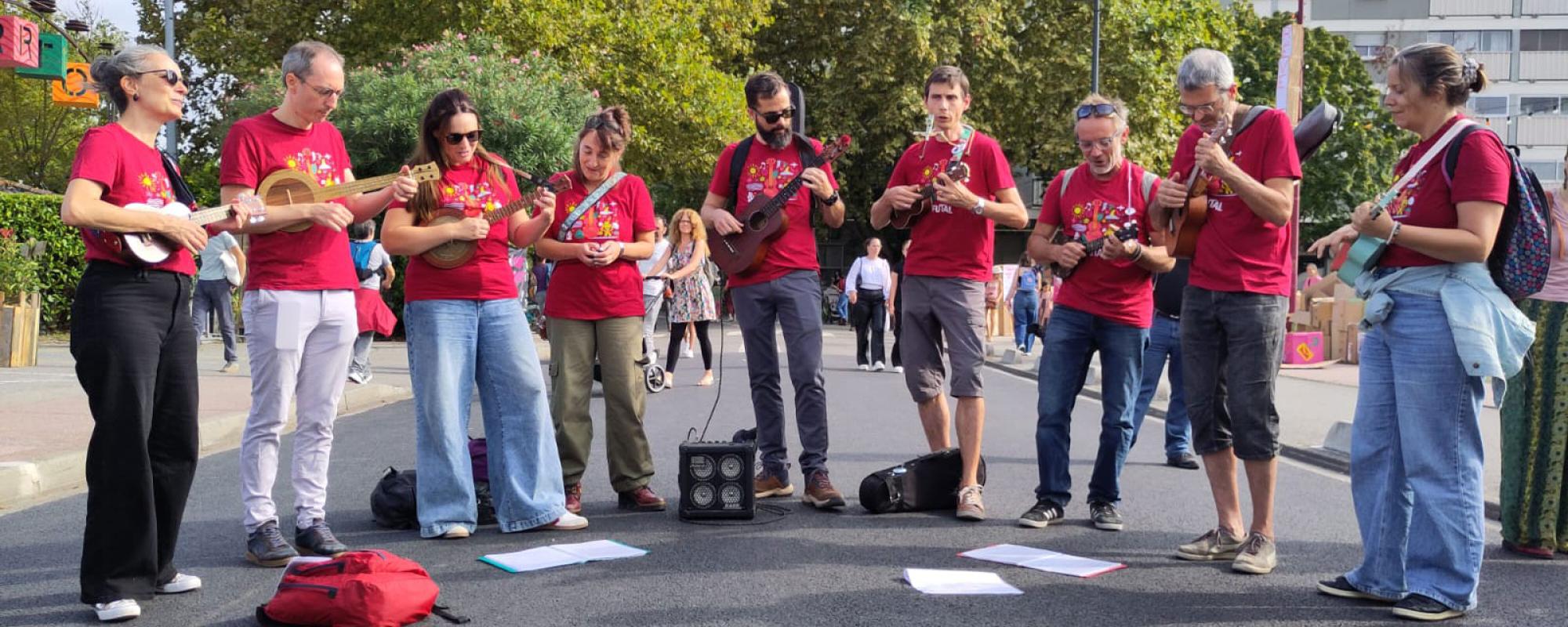 Neuf musiciens et musiciennes du groupe avec leurs instruments, dans une rue de Ramonville lors du Festival de rue