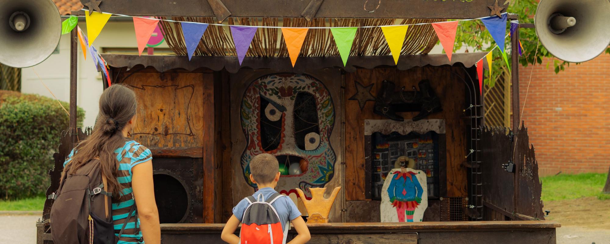 Une femme et un enfant, de dos, regardent le stand de tir, décoré de fanions.
