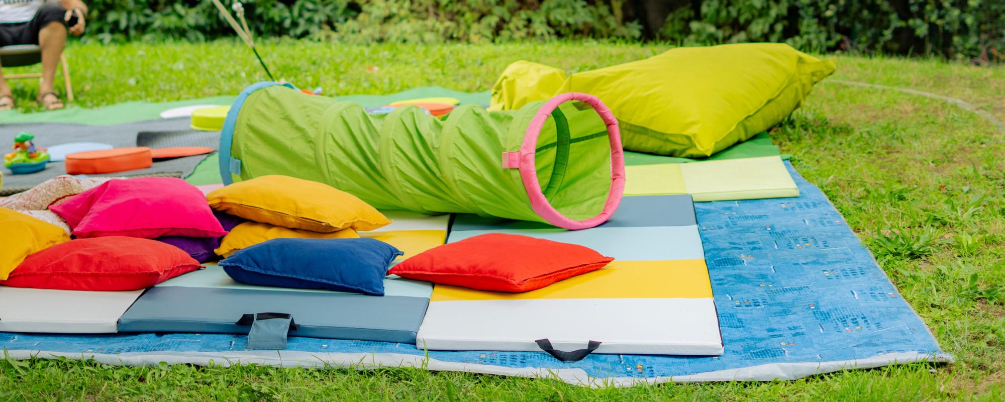 Espace pour les enfants avec tapis, coussins et jeux colorés.